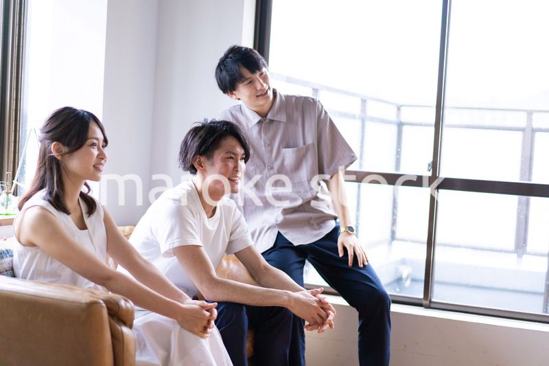 家でスポーツの試合を観戦する若い男女