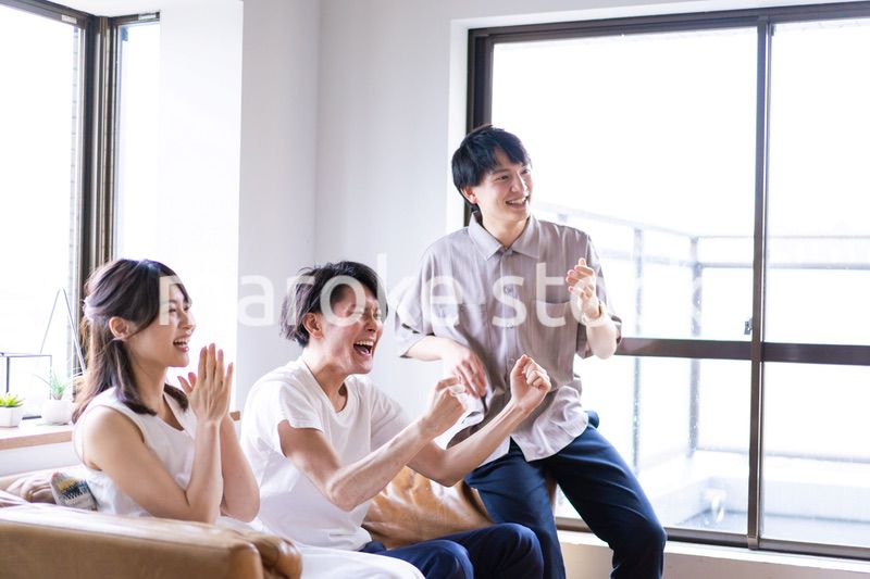 家でスポーツの試合を観戦する若い男女