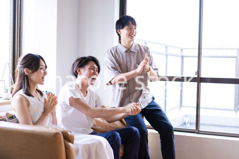 家でスポーツの試合を観戦する若い男女