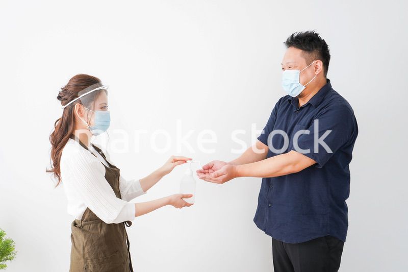 手のアルコール消毒をお願いするカフェスタッフ