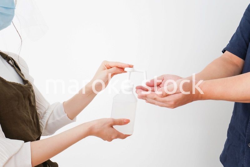 手のアルコール消毒をお願いするカフェスタッフ