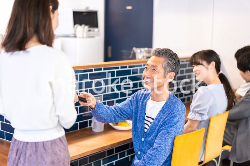 飲食店で電子マネー決済をする男性