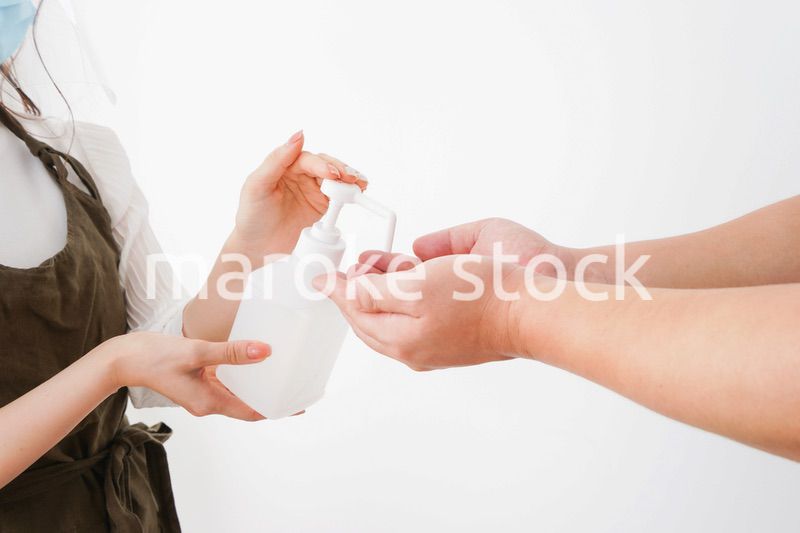 手のアルコール消毒をお願いするカフェスタッフ