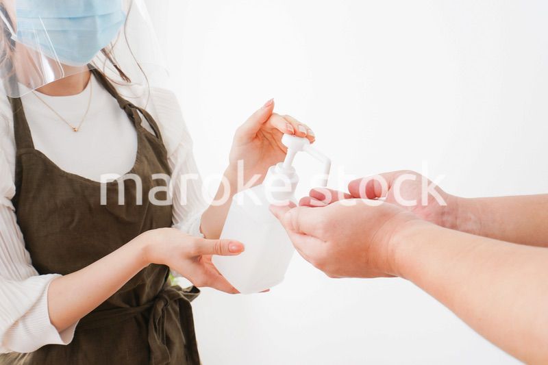 手のアルコール消毒をお願いするカフェスタッフ