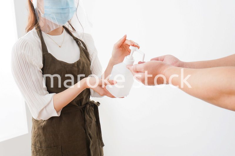 手のアルコール消毒をお願いするカフェスタッフ