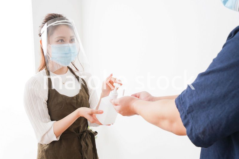 手のアルコール消毒をお願いするカフェスタッフ