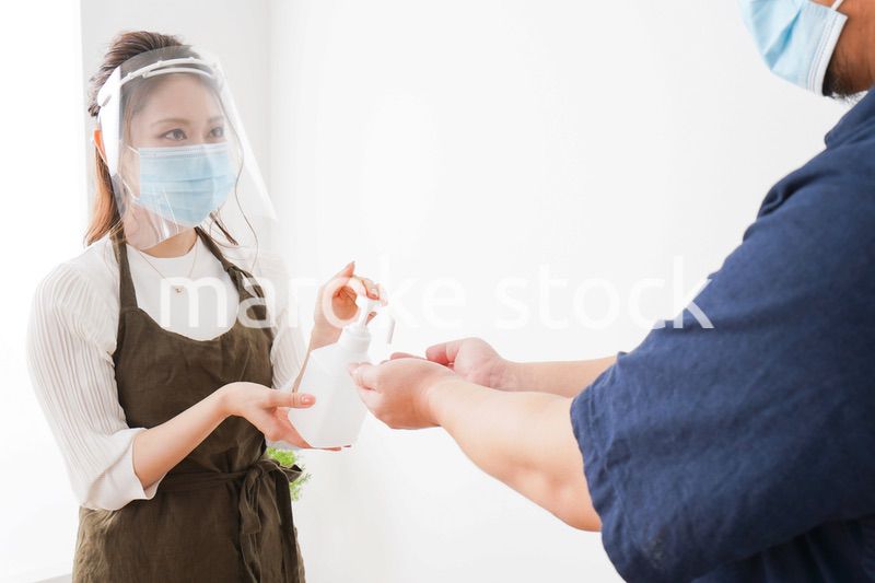 手のアルコール消毒をお願いするカフェスタッフ