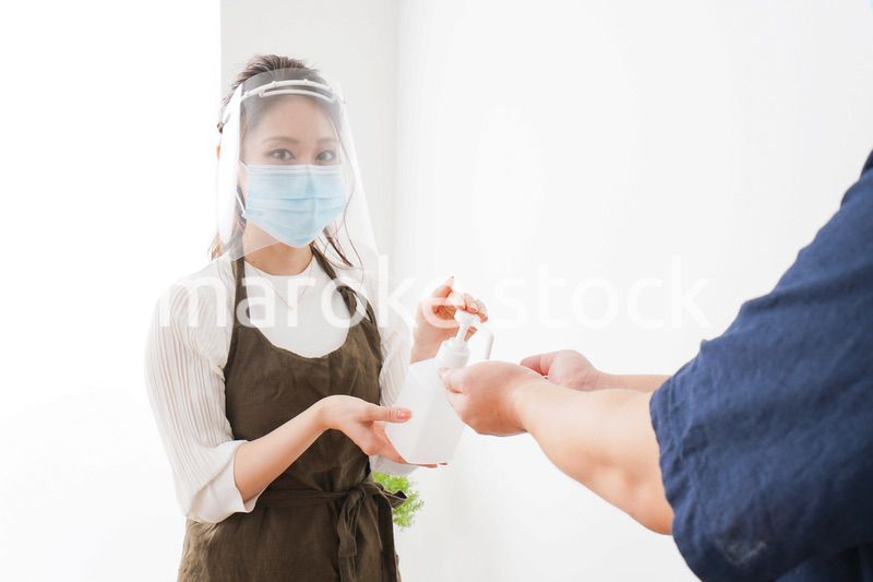 手のアルコール消毒をお願いするカフェスタッフ