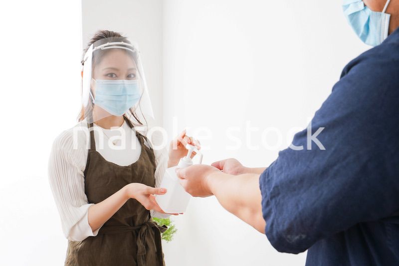 手のアルコール消毒をお願いするカフェスタッフ