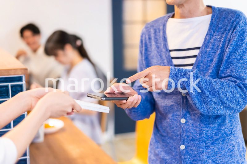 飲食店で電子マネー決済をする男性