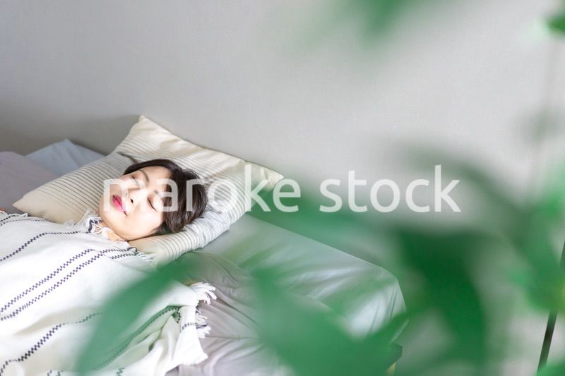 ベッドで熟睡する若い女性