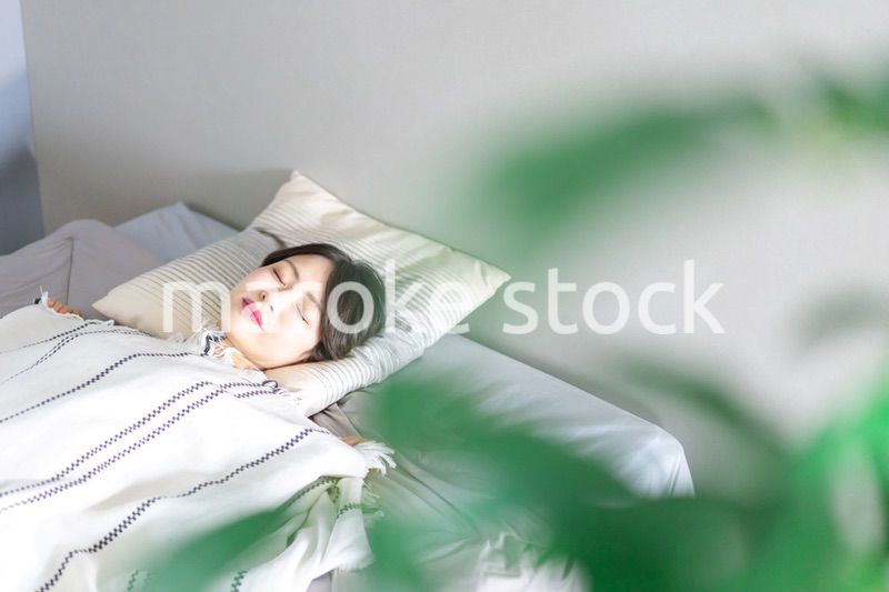 ベッドで熟睡する若い女性