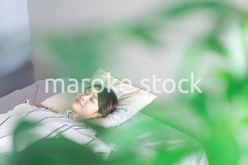 ベッドで熟睡する若い女性