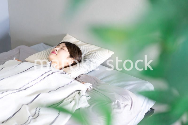 ベッドで熟睡する若い女性