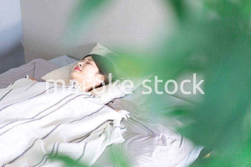 ベッドで熟睡する若い女性