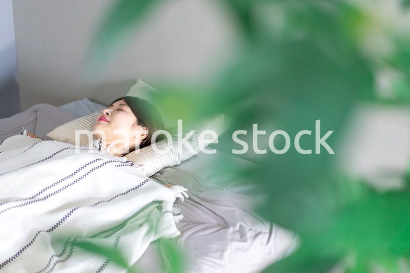 ベッドで熟睡する若い女性