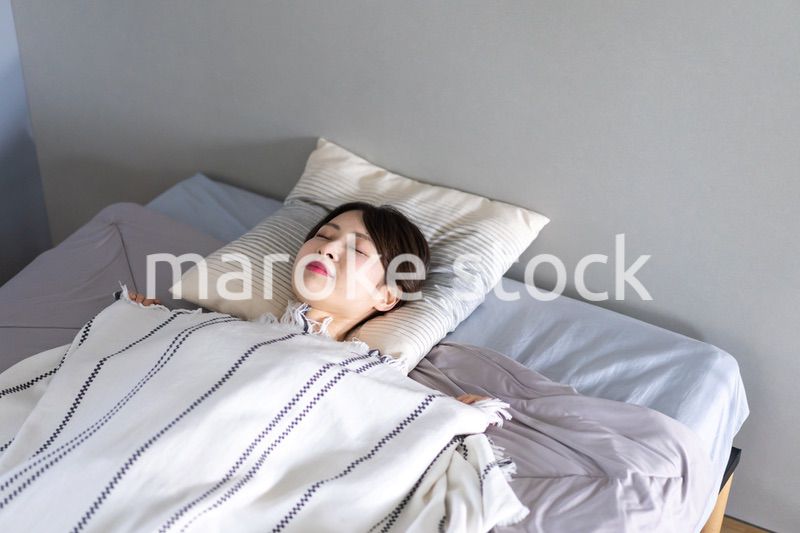 ベッドで熟睡する若い女性