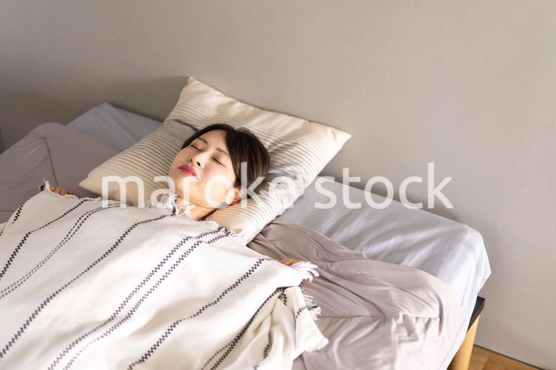 ベッドで熟睡する若い女性