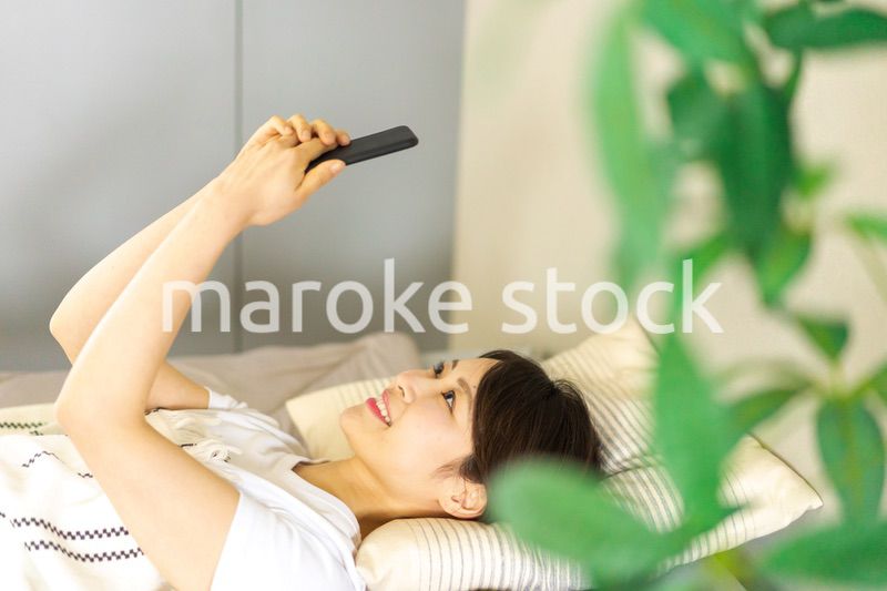 ベッドでスマホを使う若い女性