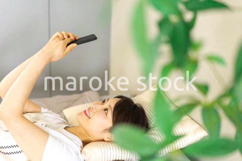 ベッドでスマホを使う若い女性