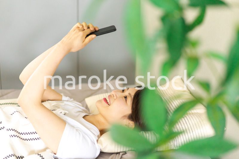 ベッドでスマホを使う若い女性