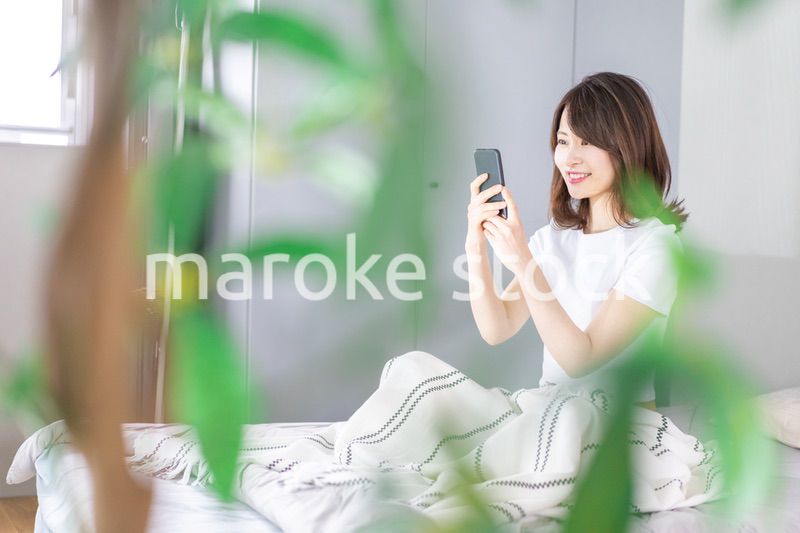 ベッドでスマホを使う若い女性
