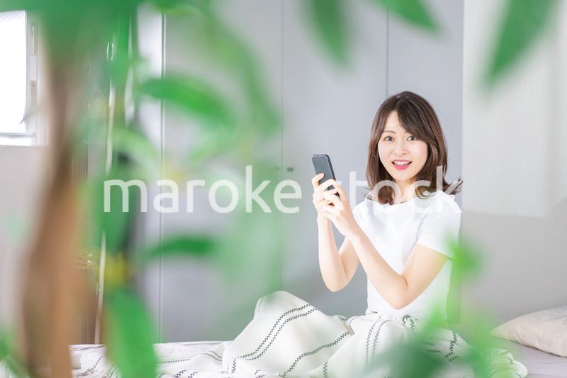 ベッドでスマホを使う若い女性