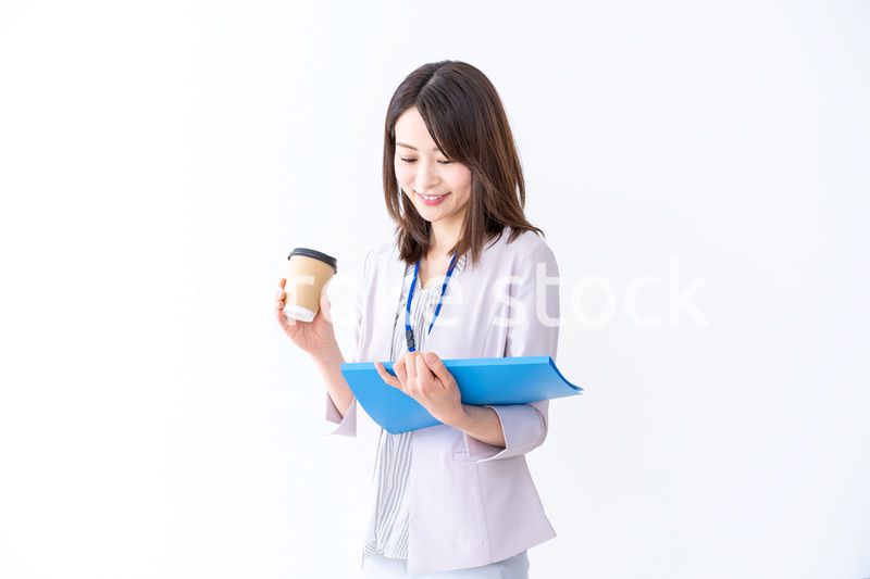 コーヒーを持ってオフィスを歩く美人のビジネスウーマン