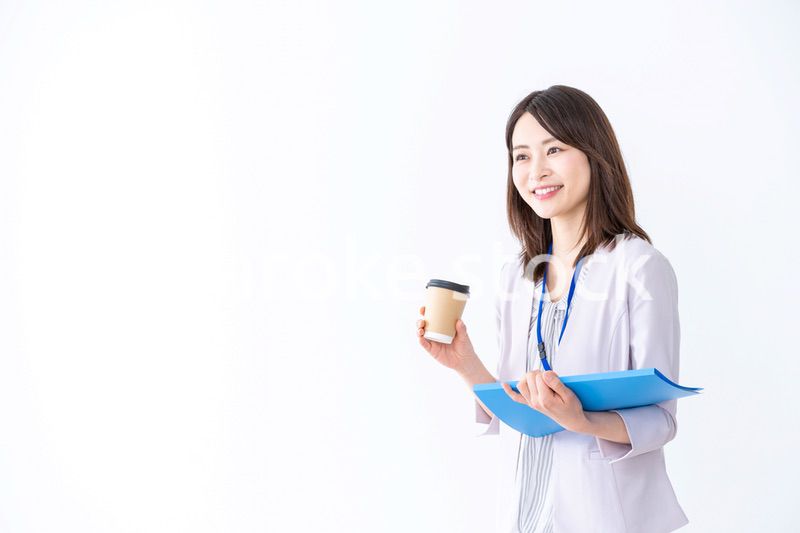 コーヒーを持ってオフィスを歩く美人のビジネスウーマン