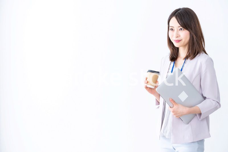 コーヒーを持ってオフィスを歩く美人のビジネスウーマン