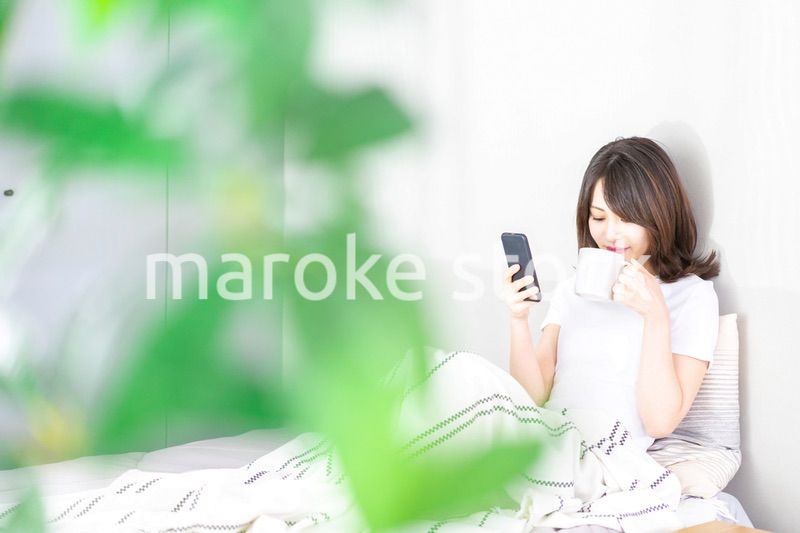 ベッドでスマホを使う若い女性