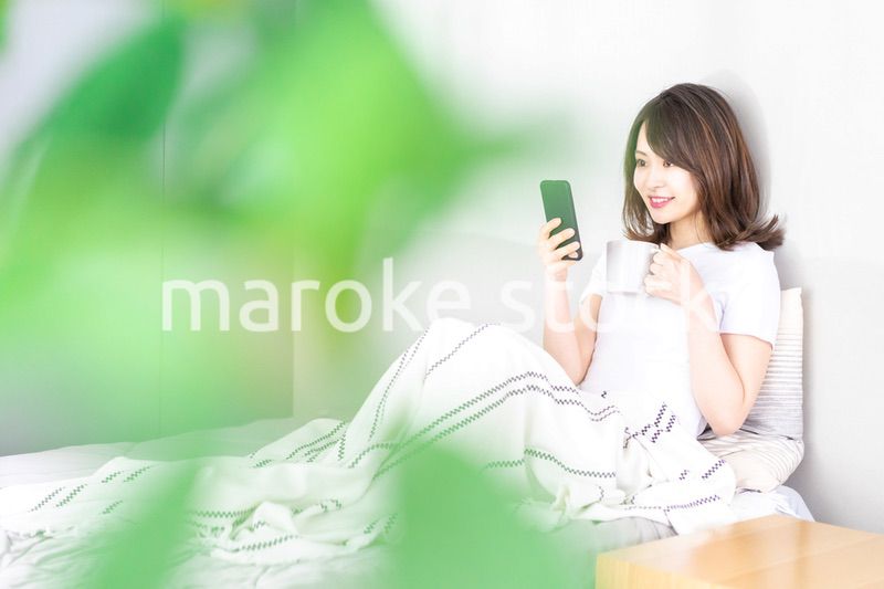 ベッドでスマホを使う若い女性