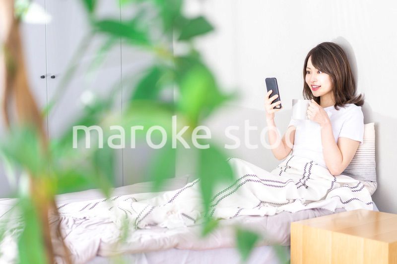 ベッドでスマホを使う若い女性