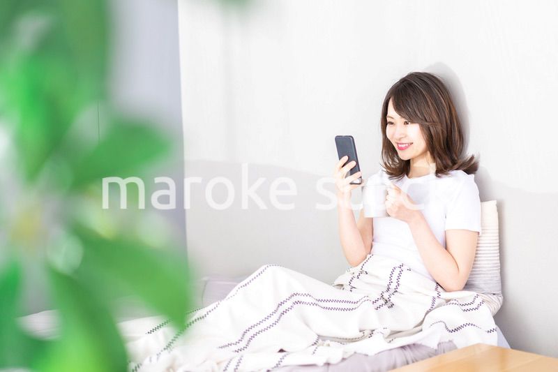 ベッドでスマホを使う若い女性