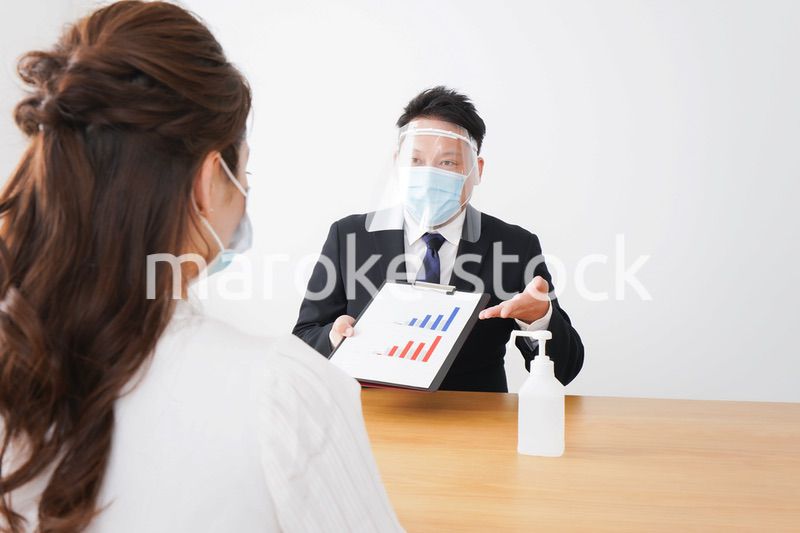 フェイスシールドとマスクをして商談をするビジネスパーソン