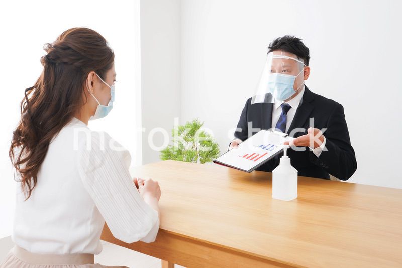 フェイスシールドとマスクをして商談をするビジネスパーソン