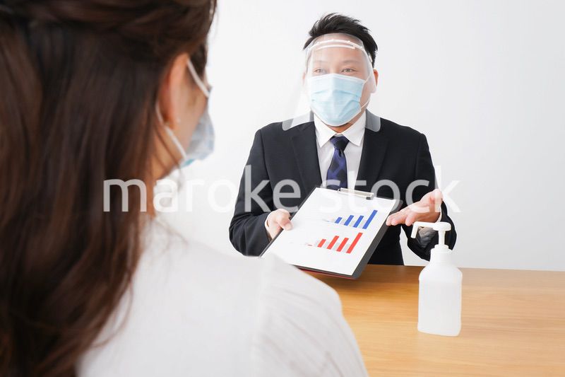 フェイスシールドとマスクをして商談をするビジネスパーソン
