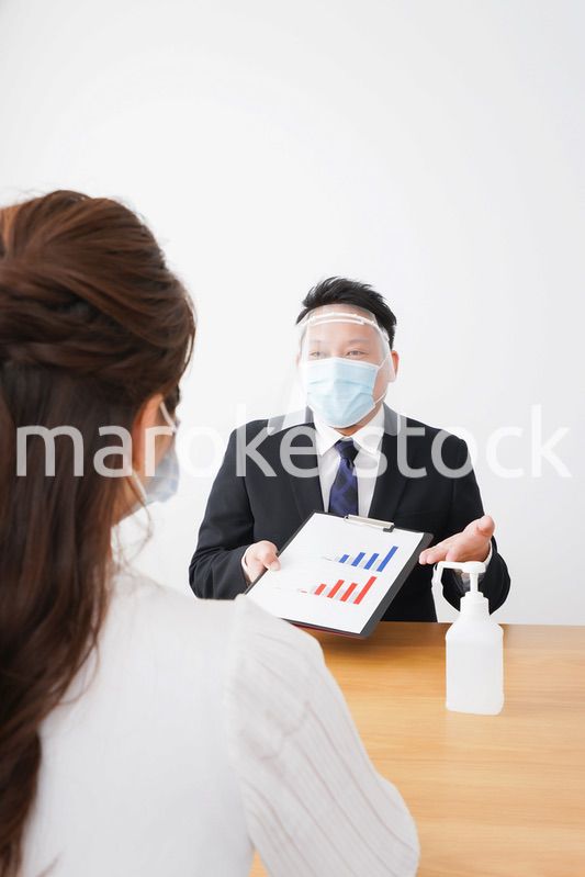 フェイスシールドとマスクをして商談をするビジネスパーソン