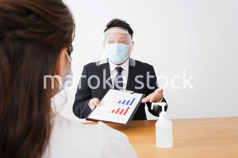 フェイスシールドとマスクをして商談をするビジネスパーソン