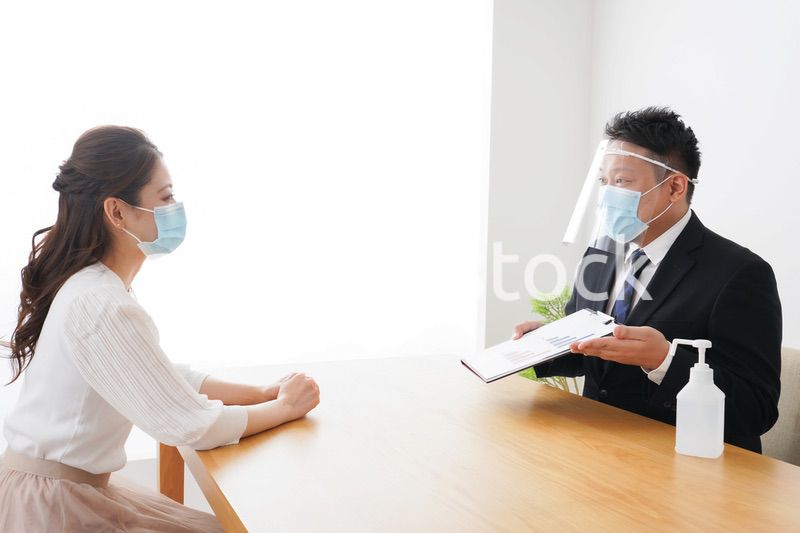 フェイスシールドとマスクをして商談をするビジネスパーソン