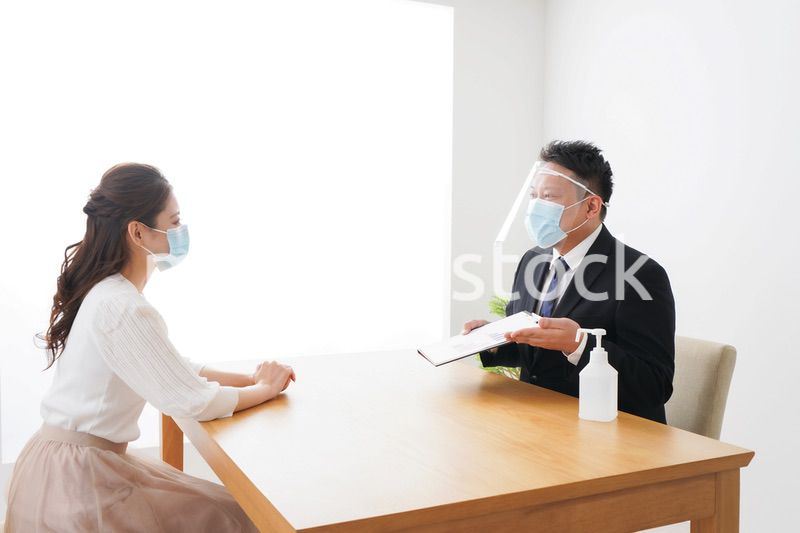 フェイスシールドとマスクをして商談をするビジネスパーソン