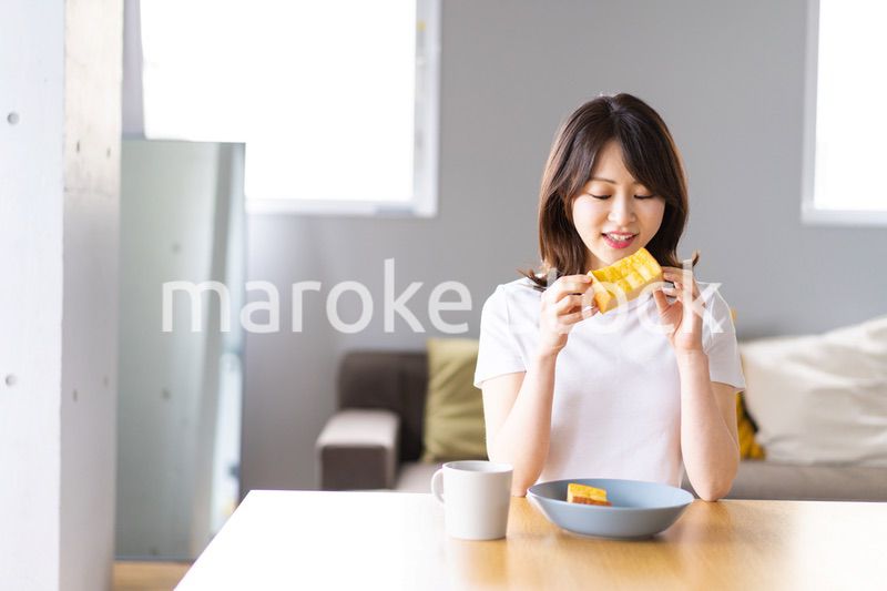 自宅で朝食を食べる若い女性