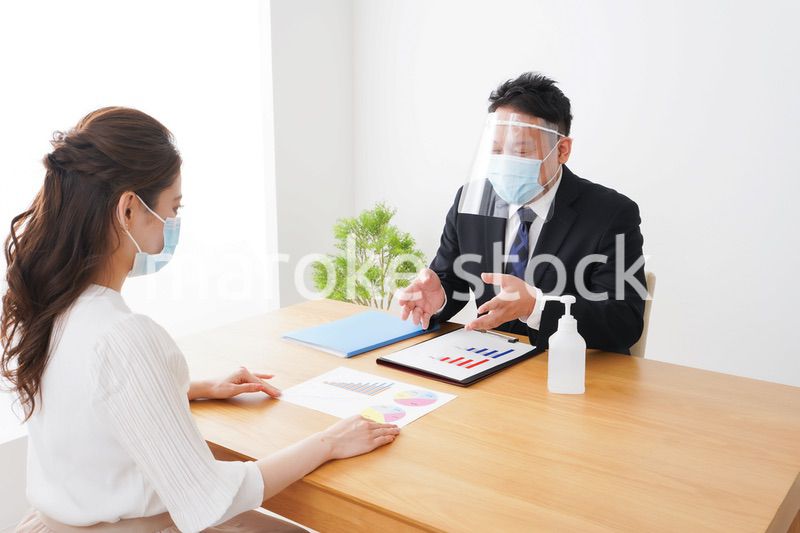 フェイスシールドとマスクをして商談をするビジネスパーソン