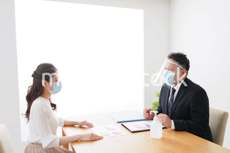 フェイスシールドとマスクをして商談をするビジネスパーソン