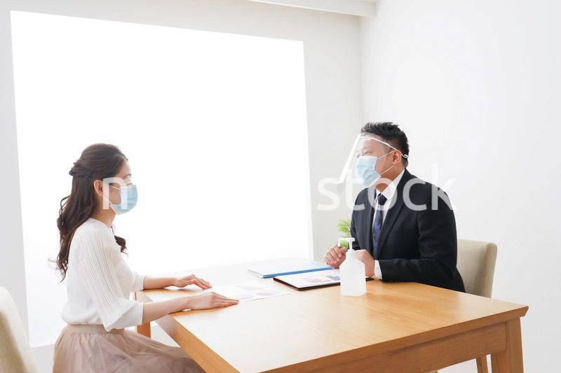 フェイスシールドとマスクをして商談をするビジネスパーソン