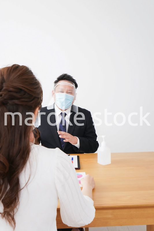 フェイスシールドとマスクをして商談をするビジネスパーソン