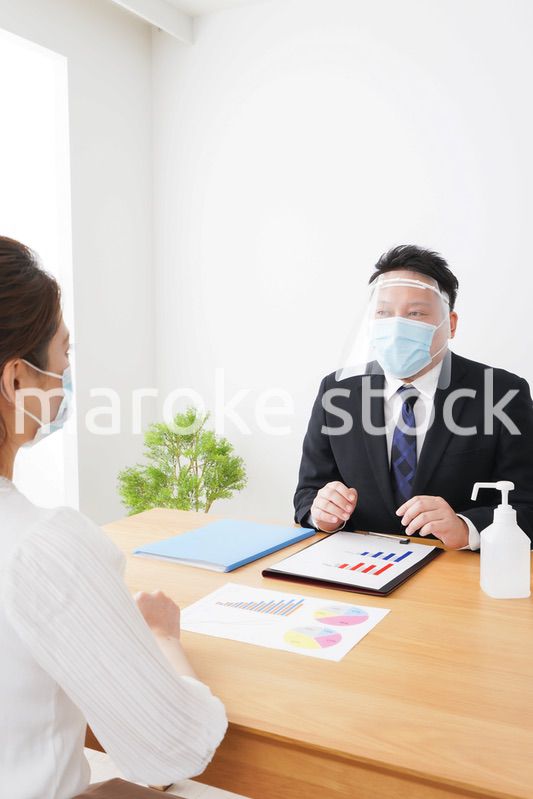 フェイスシールドとマスクをして商談をするビジネスパーソン