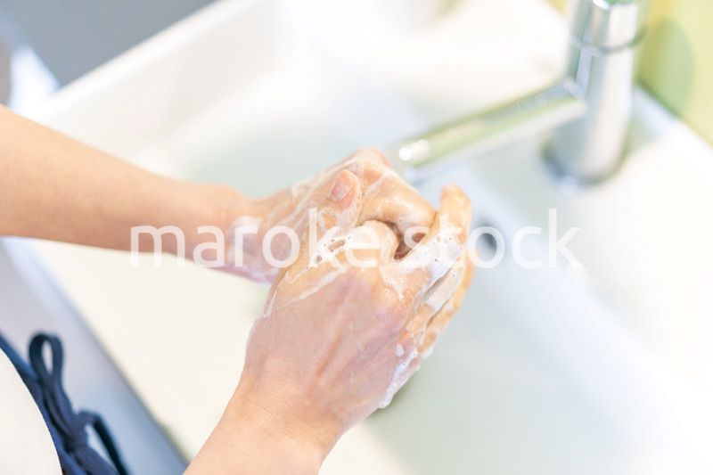 洗面台で顔を洗う若い女性