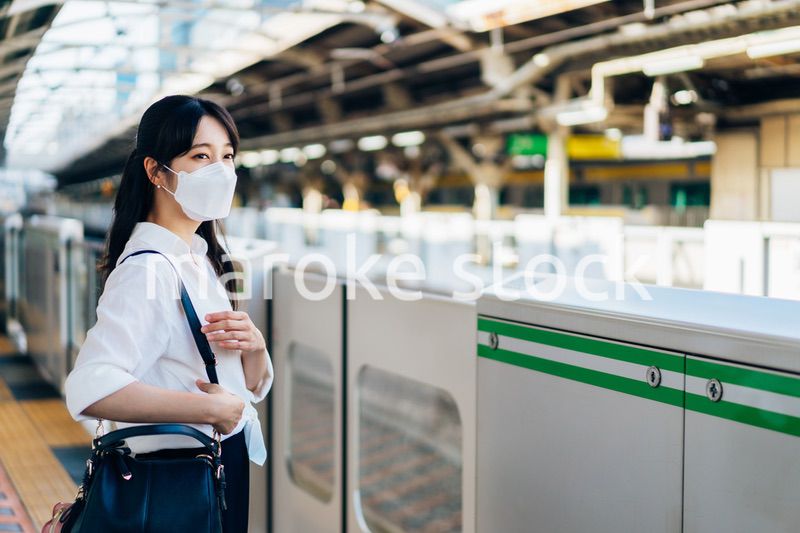 マスクをして電車を待つ若い女性