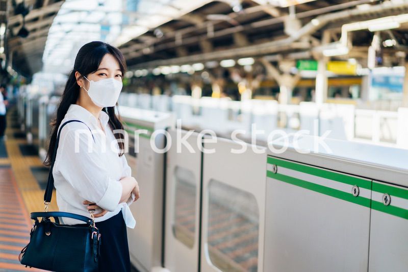 マスクをして電車を待つ若い女性